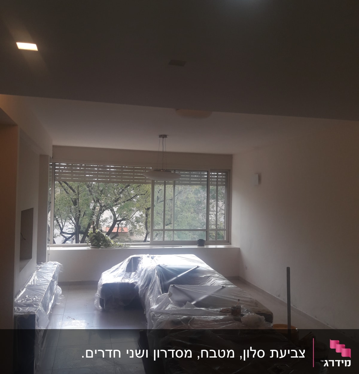 חדר עם רהיטים מכוסים בניילון לקראת צביעה